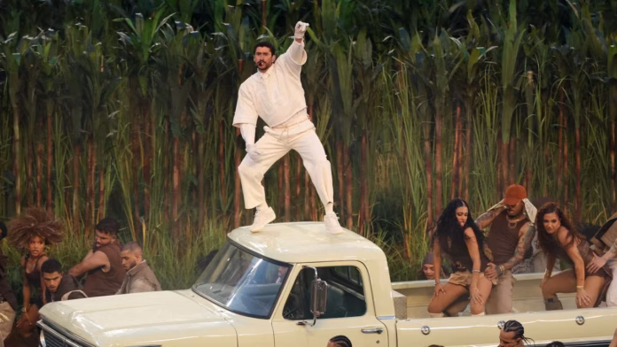 Bad Bunny sobre un coche en el escenario del Super Bowl LX, vestido de blanco, en medio de luces y visuales latinos durante su show histórico.